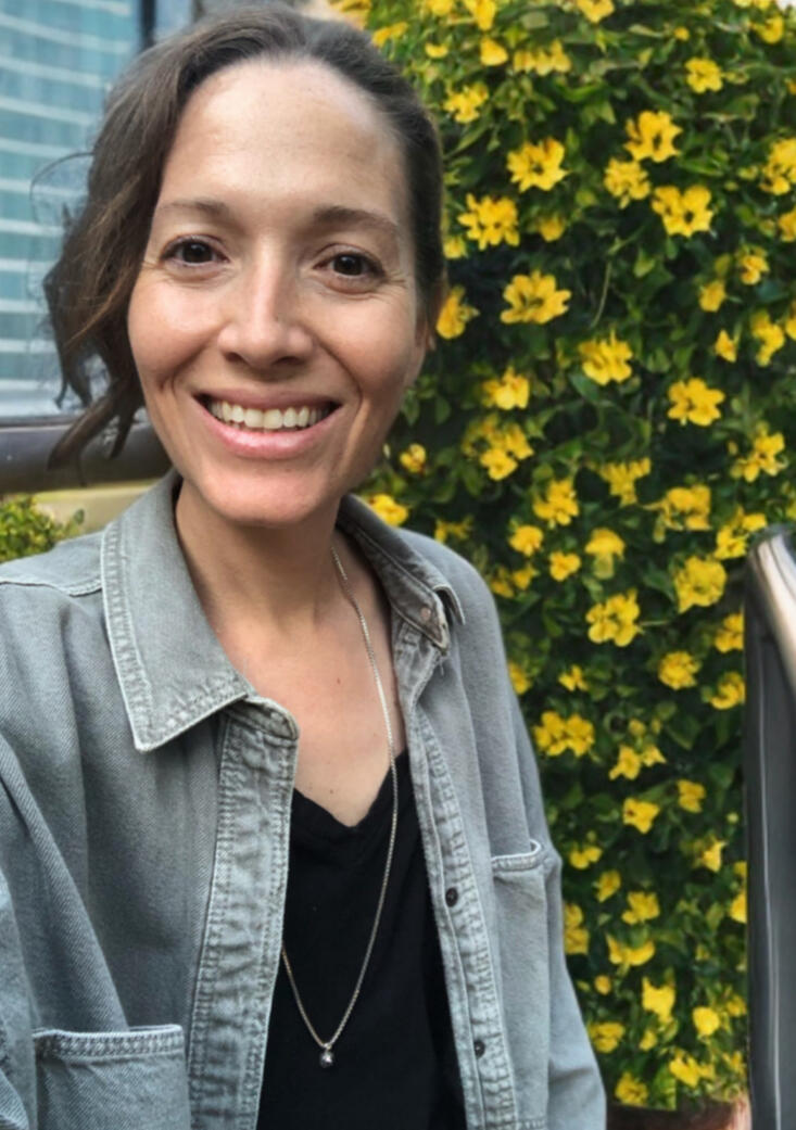 Jill smiling outdoors with yellow flowers in the background